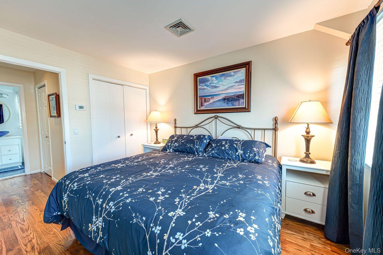 49 Canoe Place Road, Unit 212 Hampton Bays, NY 11946 - Photo 8 of 22 a bedroom with a bed and a lamp on dresser