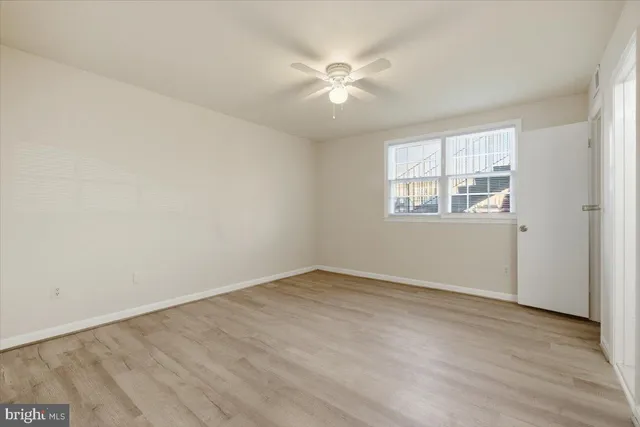 an empty room with wooden floor fan and windows