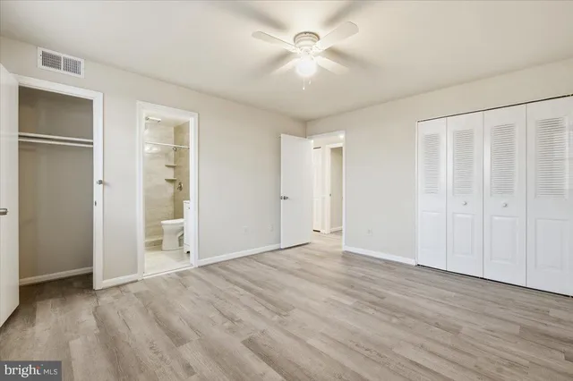 a view of empty room with wooden floor and fan