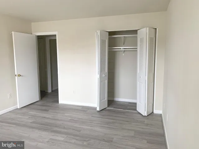 a view of an empty room with wooden floor and closet