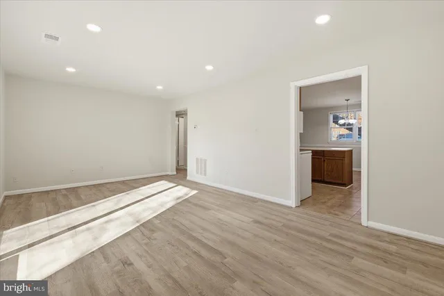 an empty room with wooden floor and natural light