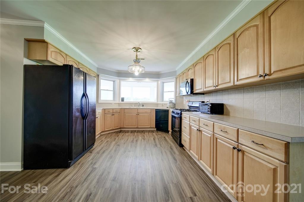 6460 Talley Road Stanfield, NC 28163 - Photo 32 of 47 a kitchen with cabinets wooden floor and stainless steel appliances
