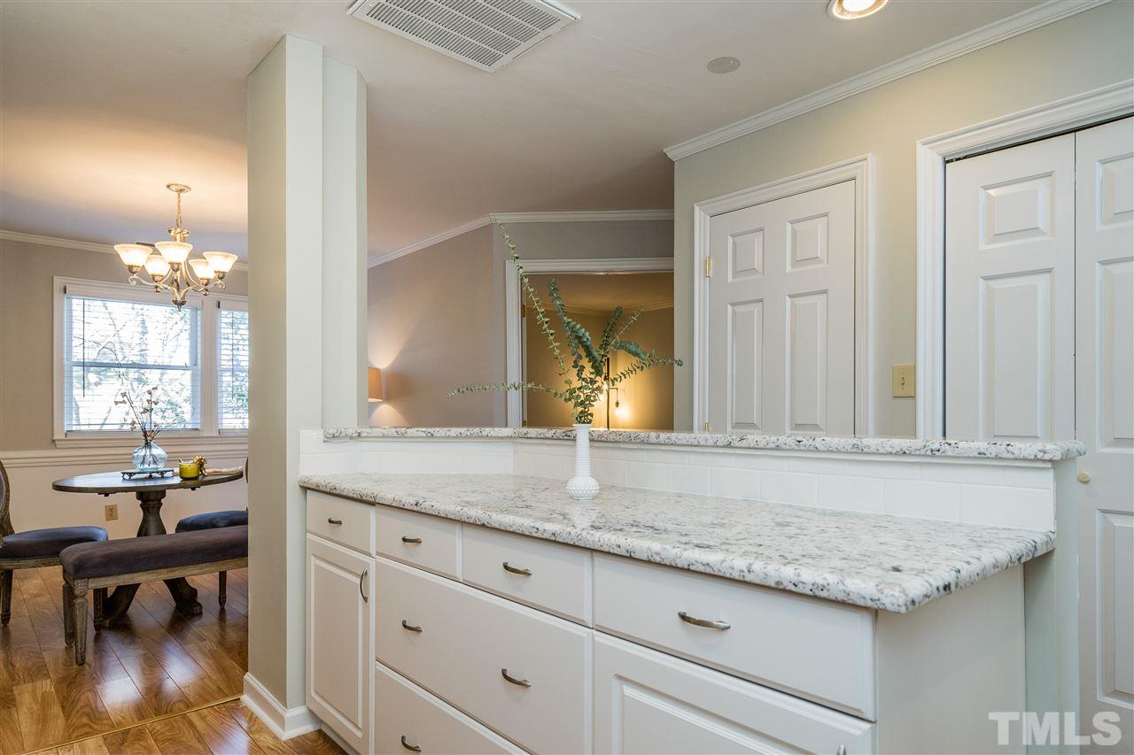 7010 Sandy Forks Road, Unit 207 Raleigh, NC 27615 - Photo 15 of 27 a view of a granite countertop kitchen island with a sink and dishwasher a dining table with wooden floor