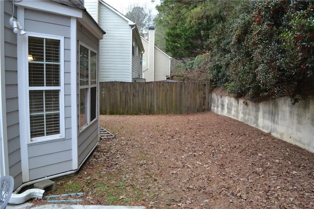 a view of backyard with large tree and wooden fence