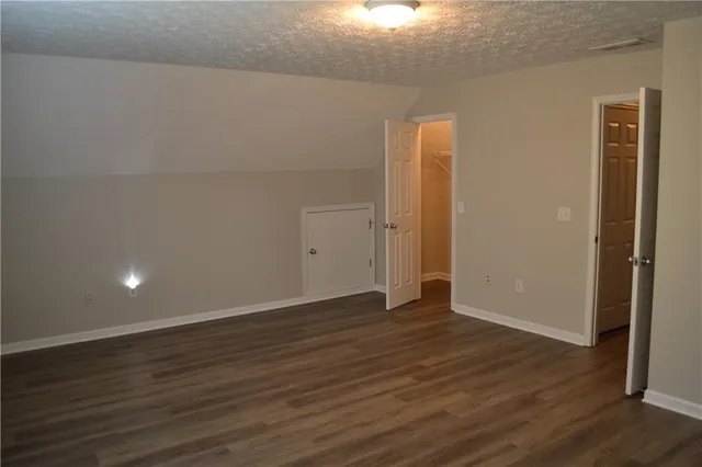 a view of an empty room with wooden floor and closet
