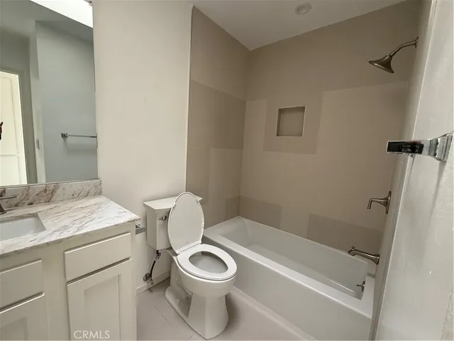 a bathroom with a granite countertop toilet a sink and a bathtub