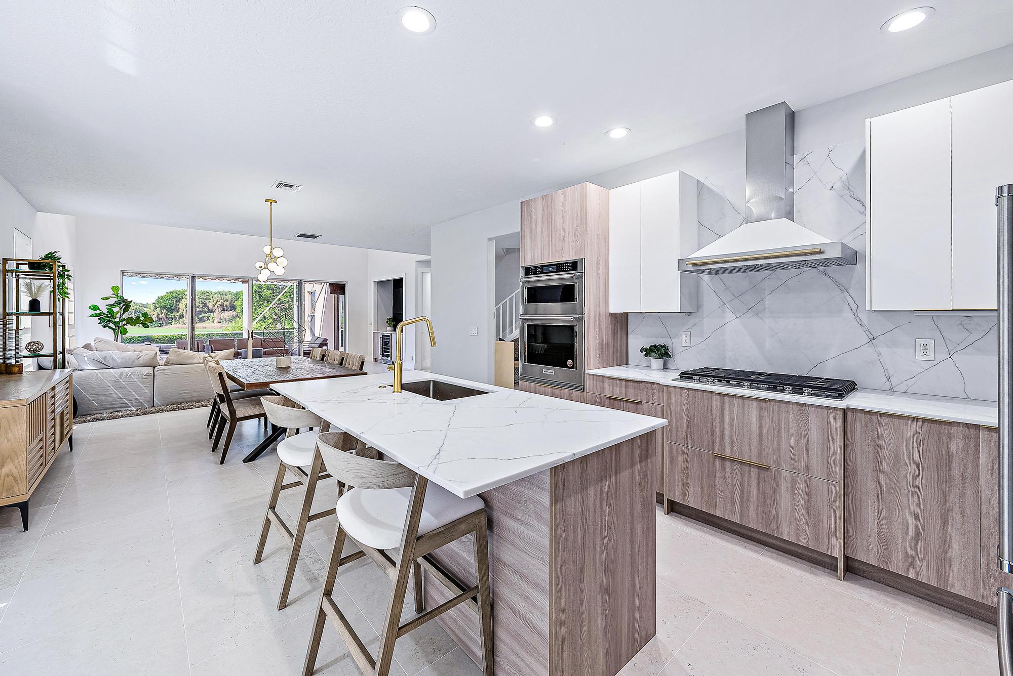 a kitchen with stainless steel appliances a table chairs sink and cabinets