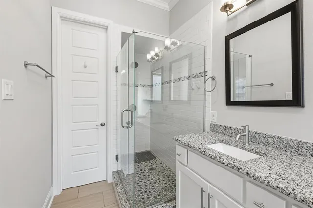 a bathroom with a granite countertop sink a mirror a vanity and a shower