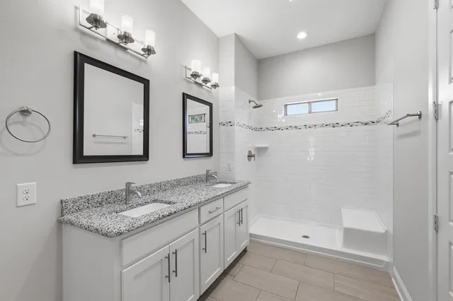 a bathroom with a granite countertop sink a mirror a vanity and shower