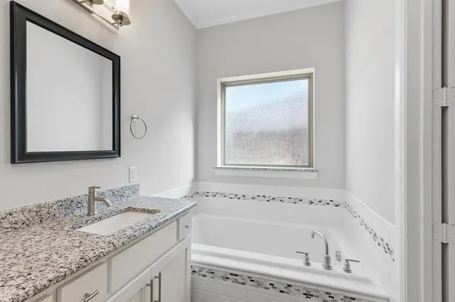 a bathroom with a granite countertop tub sink and mirror