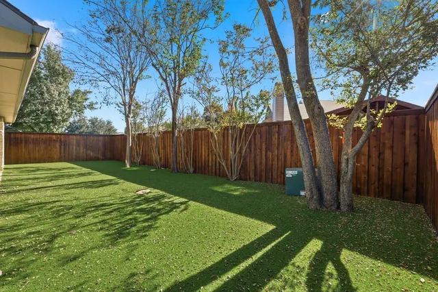 a view of a backyard with large trees and wooden fence
