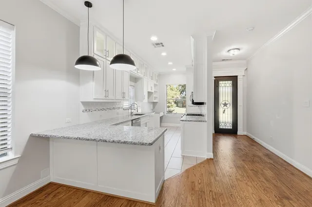 a kitchen with stainless steel appliances granite countertop a sink a island with wooden cabinets and floors
