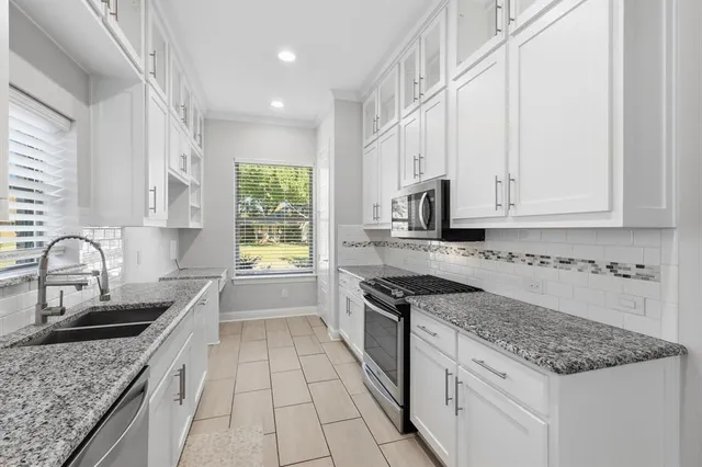 a kitchen with granite countertop a sink stainless steel appliances and cabinets