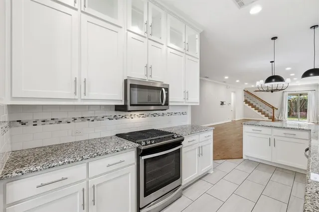 a kitchen with granite countertop white cabinets and white appliances