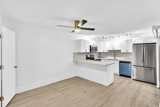 a kitchen with a refrigerator and white cabinets