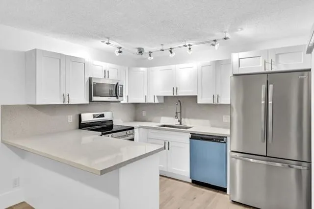 a kitchen with stainless steel appliances a refrigerator stove microwave and sink