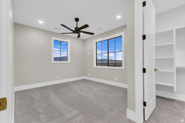 2828 Jojo Road Eagle Mountain, UT 84005 - Photo 30 of 63 Room featuring two windows with black grilles, a dark-toned ceiling fan, recessed lighting, and light-toned carpeting