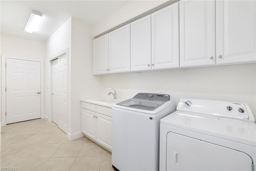 13366 Kent Street Naples, FL 34109 - Photo 17 of 23 Laundry area with light tile patterned floors, washing machine and dryer, and cabinet space