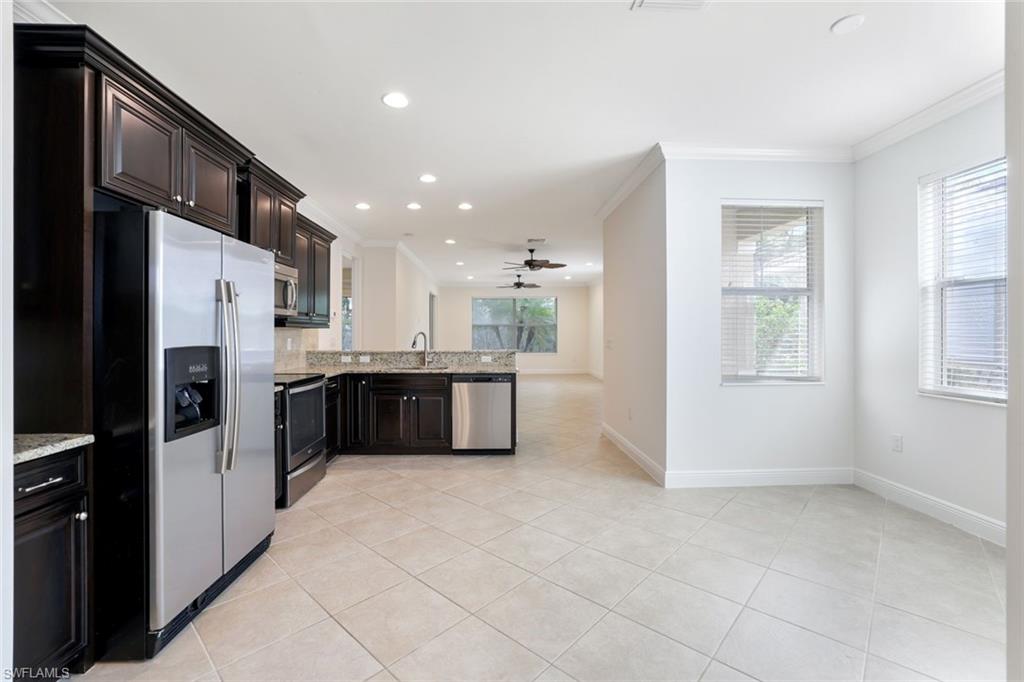 13366 Kent Street Naples, FL 34109 - Photo 6 of 23 Kitchen featuring appliances with stainless steel finishes, light tile patterned floors, recessed lighting, light stone counters, and a peninsula