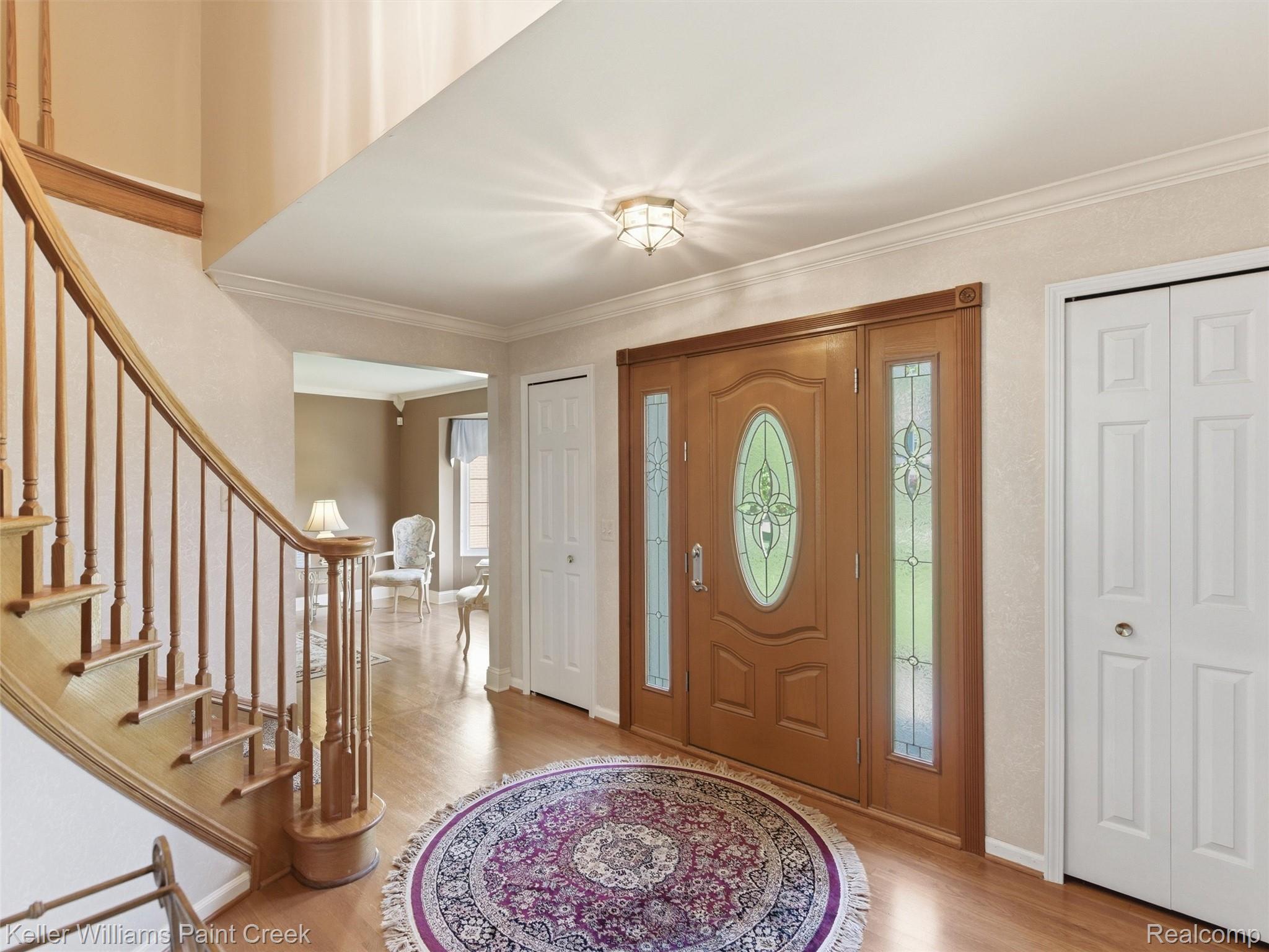 2842 Manorwood Road Troy, MI 48085 - Photo 19 of 72 Entry foyer with wood-finish flooring, a grand curved staircase with wood banister, and a paneled front door with decorative stained glass