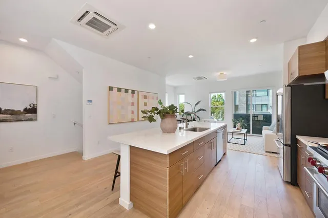 a kitchen with stainless steel appliances kitchen island wooden cabinets a sink a stove and a refrigerator