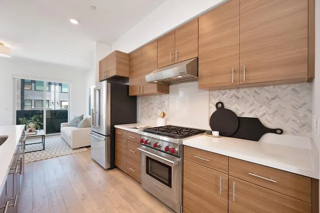 a kitchen with stainless steel appliances a dining table chairs and wooden floor