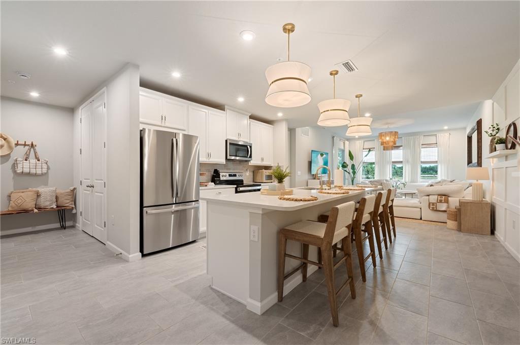 4638 Arboretum Circle, Unit 102 Naples, FL 34112 - Photo 18 of 20 a kitchen with stainless steel appliances a table chairs and chandelier