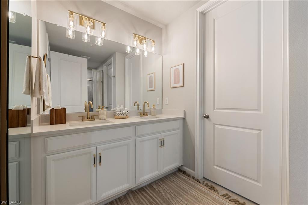 4638 Arboretum Circle, Unit 102 Naples, FL 34112 - Photo 6 of 20 a bathroom with a double vanity sink and a mirror