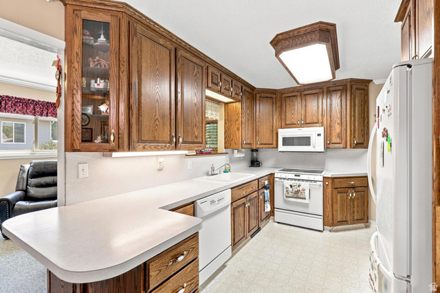 702 North 150 West Logan, UT 84321 - Photo 14 of 51 Kitchen featuring wood-finish cabinetry, solid surface countertops, a built-in microwave, and a white appliance package