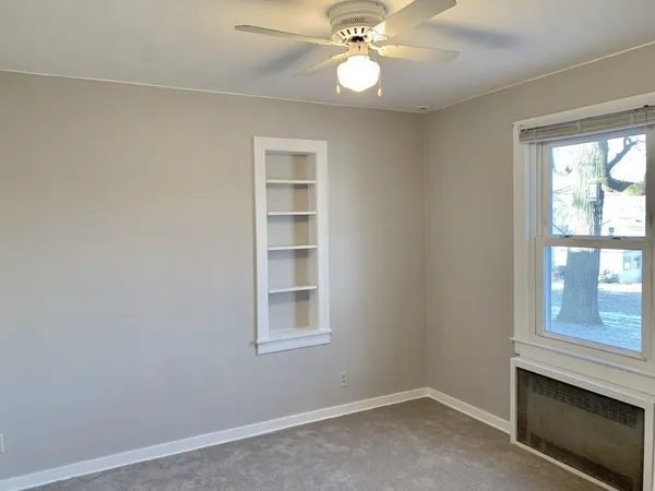 an empty room with windows and fan