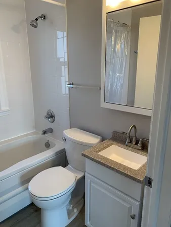 a bathroom with a granite countertop toilet a sink and a bathtub