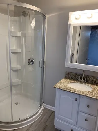 a bathroom with a granite countertop sink a mirror and shower
