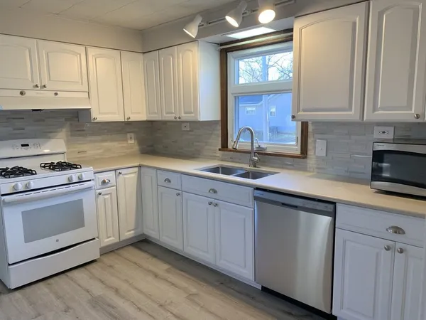 a kitchen with granite countertop white cabinets and white appliances
