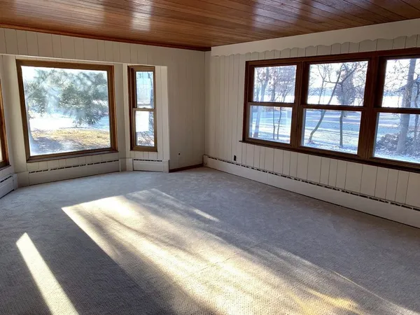 a view of an empty room with a fireplace and windows