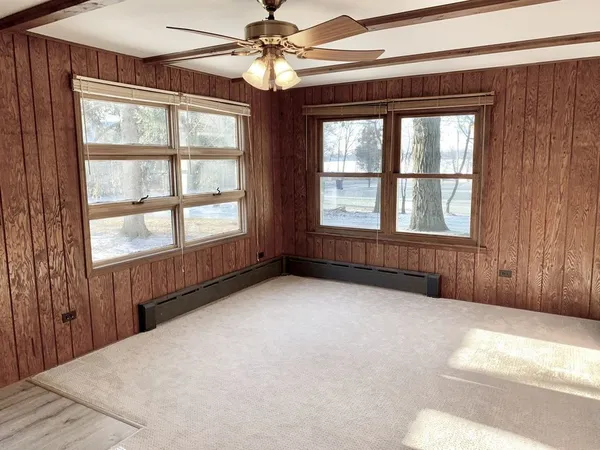 an empty room with chandelier fan and windows