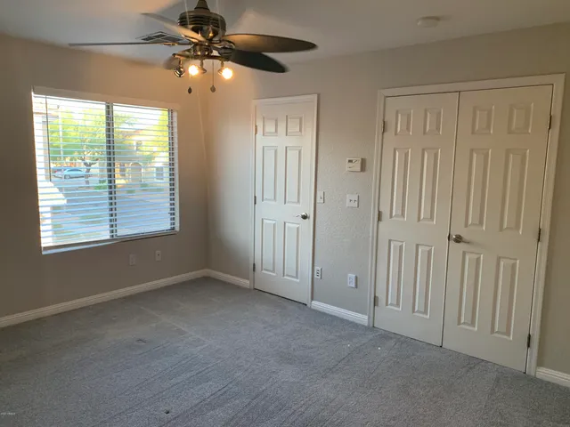 en empty room with windows and chandelier fan