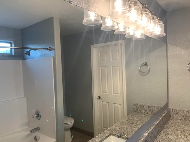 a bathroom with a granite countertop sink a toilet and shower