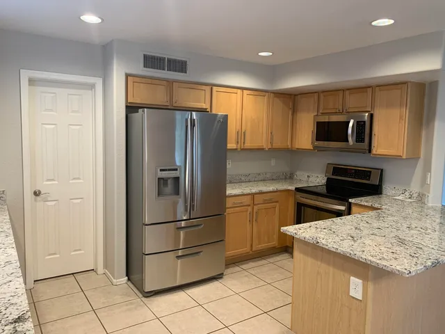 a kitchen with stainless steel appliances granite countertop a refrigerator and a stove top oven