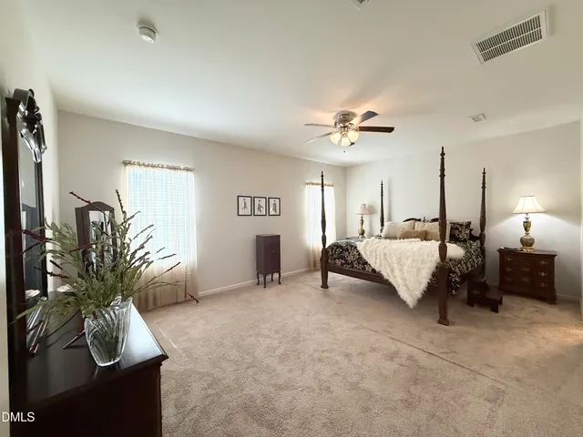 a spacious bedroom with a bed a couch and a potted plant