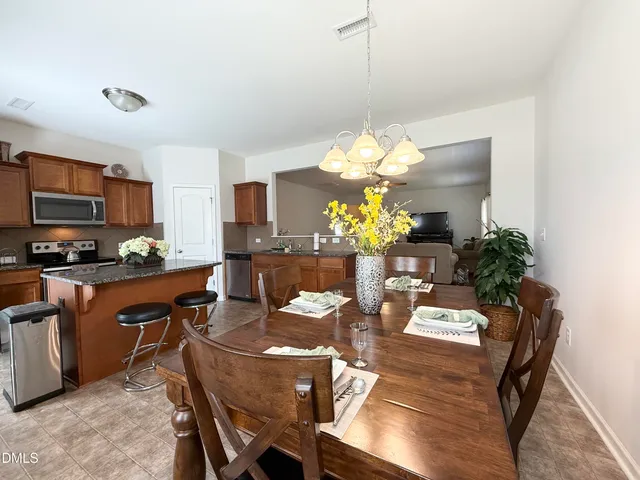 a dining room filled chandelier and wooden floor