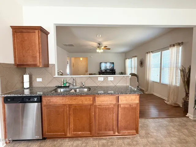 a large kitchen with kitchen island granite countertop wooden cabinets a sink and dishwasher