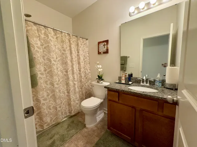 a bathroom with a granite countertop sink toilet and mirror