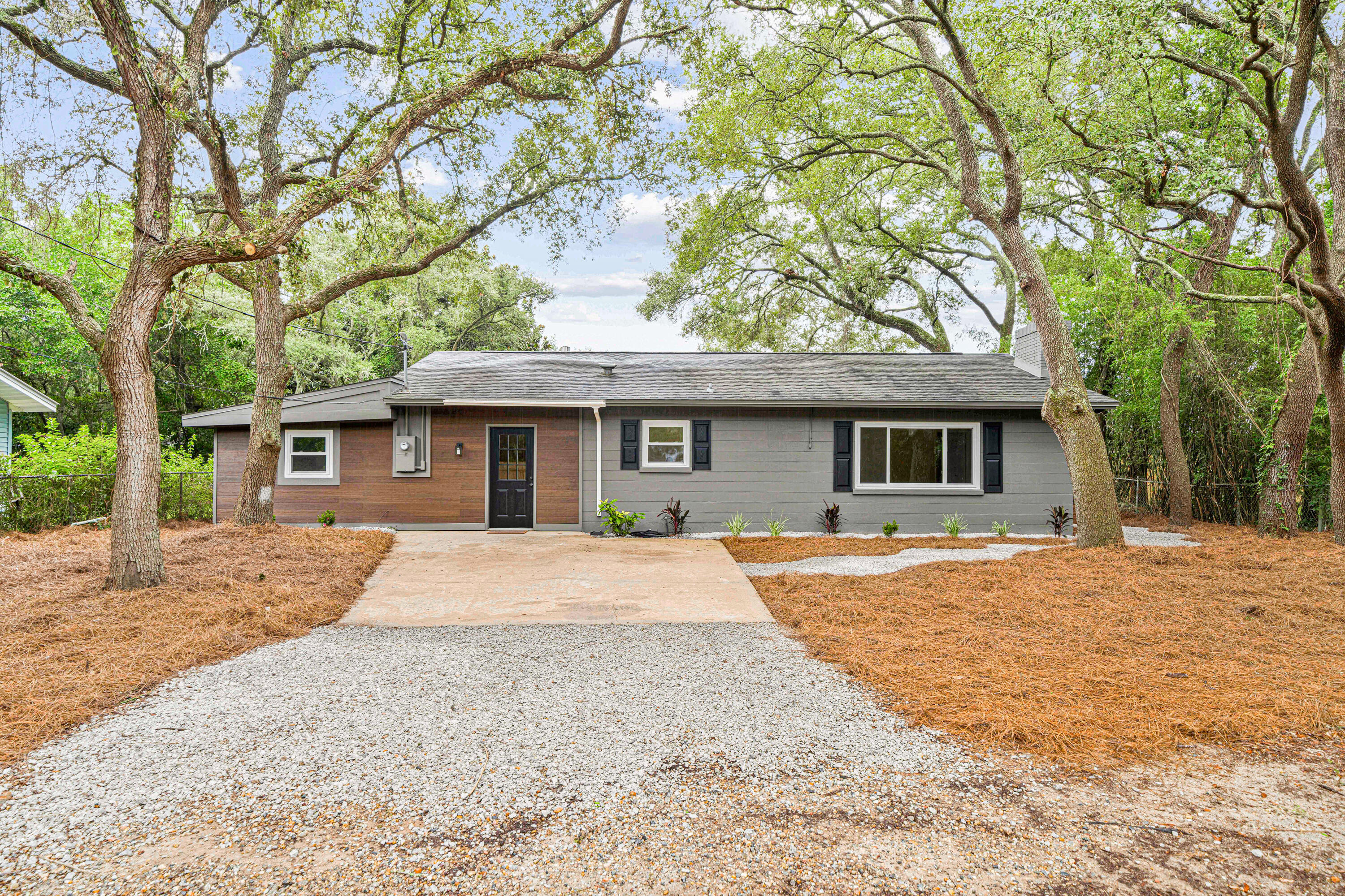 a front view of a house with a garden and trees