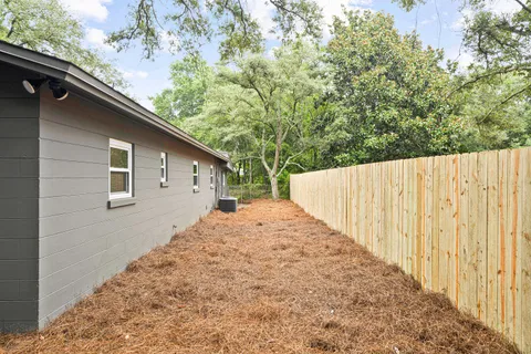 a view of house with backyard and trees in the background
