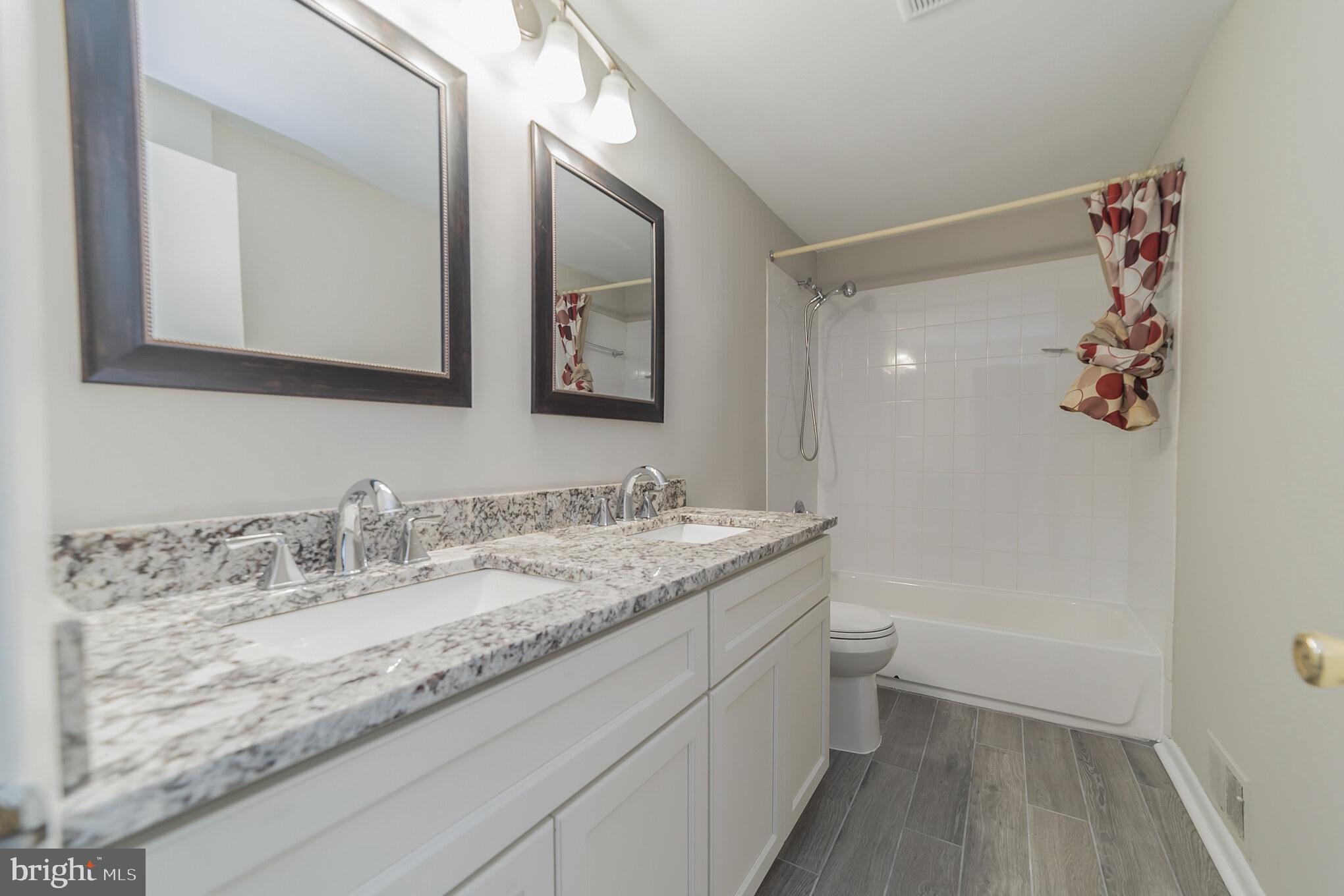 9349 Reader Lane Columbia, MD 21045 - Photo 18 of 32 a bathroom with a granite countertop sink a toilet and a mirror