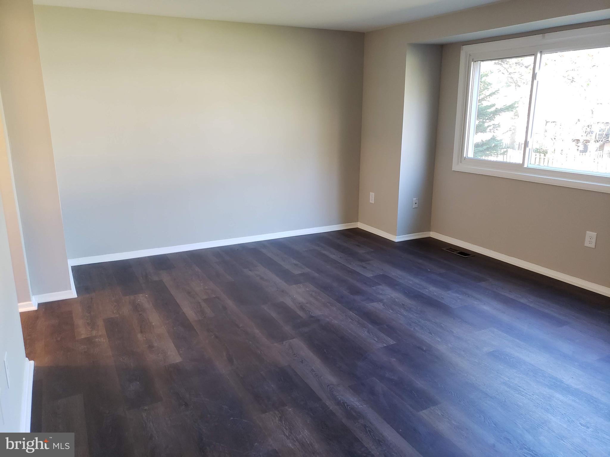 9349 Reader Lane Columbia, MD 21045 - Photo 7 of 32 an empty room with wooden floor and windows