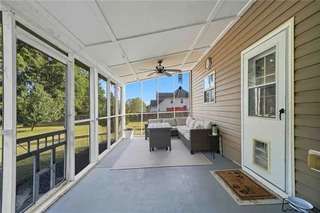 a view of a patio with couches chairs potted plants and floor to ceiling window and potted plants