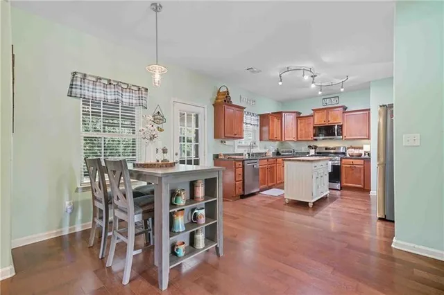 a open kitchen with stainless steel appliances granite countertop a stove top oven a sink a dining table and chairs
