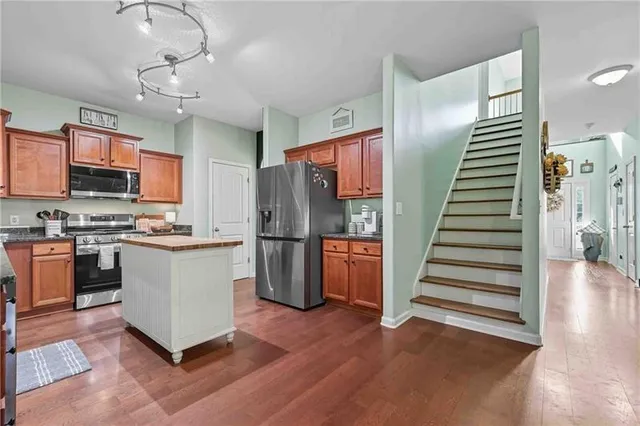 a kitchen with stainless steel appliances kitchen island wooden floor and window