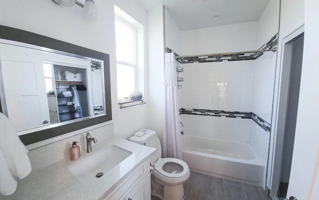 a bathroom with a bathtub shower sink vanity and a toilet